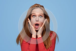 Shocked redhead woman looking at camera