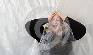 shocked sad crying screaming fat woman behind transparent plastic film, hands on head, in fear, panic, worry and despair