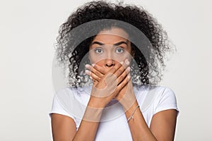 Shocked scared african woman with surprised face covering mouth