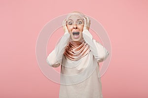 Shocked scared young arabian muslim woman in hijab light clothes posing isolated on pink background. People religious