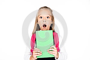 shocked schoolgirl holding book while looking at camera isolated on white.