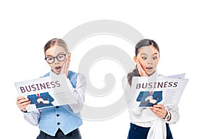 Shocked schoolgirls in formal wear reading business newspapers Isolated On White.