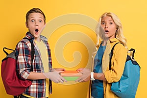 Shocked schoolkids holding books and looking at camera