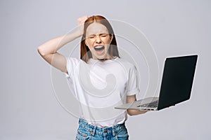 Shocked screaming young business woman or student with opened mouth holding keeping laptop computer