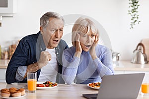 Shocked senior couple looking at laptop screen
