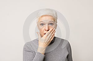 Shocked senior lady covering her mouth with hand