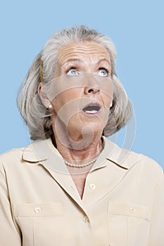 Shocked senior woman in casuals looking away against blue background