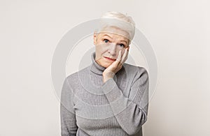 Shocked senior woman holding cheek up in total disbelief