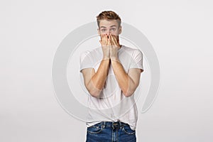 Shocked, speechless and astounded handsome blond male want scream from excitement, stare astonished, gasping cover mouth