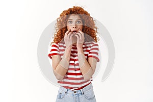 Shocked speechless concerned redhead curly woman hear terrible story look empathy worry gasping scared hold hands opened