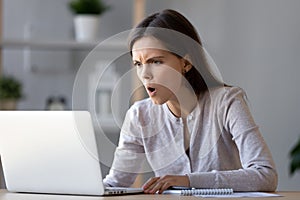 Shocked stressed woman looking at laptop reading negative surprise online