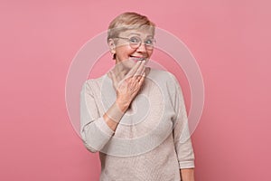 Shocked and stunned elderly woman covering mouth with palm from astonishment