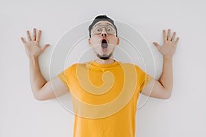 Shocked surprised face asian man yellow t-shirt eyeglasses isolated on white