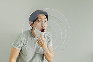 Shocked and surprised face of man wearing white hygienic mask in grey t-shirt.