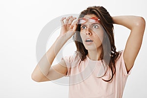 Shocked and surprised stunned attractive woman witnessing UFO in sky taking of red sunglasses staring at upper left