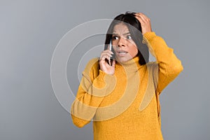 Shocked surprised woman posing isolated over grey wall background talking by mobile phone