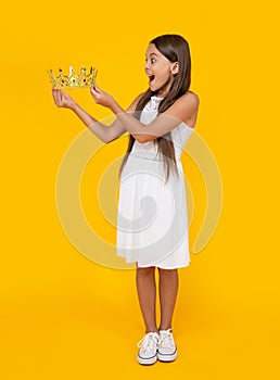 shocked teen girl in crown on yellow background