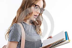 Shocked teen girl in glasses holding spiral notebook