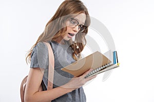 Shocked teen girl in gray t-shirt holding spiral notebook