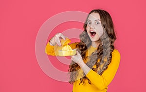 shocked teen girl hold orange and juicer on pink background