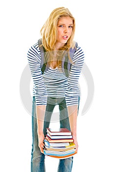 Shocked teen girl holding heavy pile of books