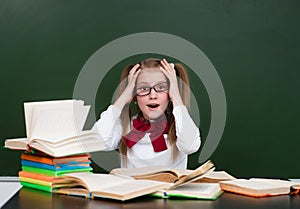 Shocked teen girl near empty green chalkboard