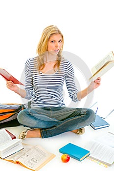 Shocked teen girl sitting on floor with books