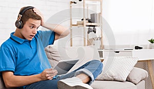 Shocked teen guy reading news on tablet