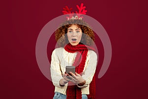 Shocked teen lady with deer antlers festive spirit of Christmas and New Year, look at phone