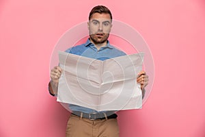 Shocked unshaved man making an astounded face while reading newspaper