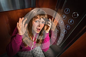 Shocked woman with claustrophobia in the moving elevator