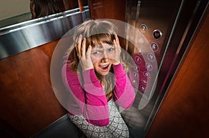 Shocked woman with claustrophobia in the moving elevator