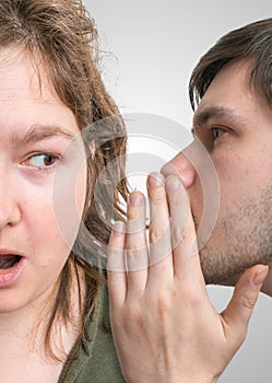 Shocked woman is listening gossip. Man is whispering to woman
