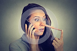 Shocked woman with long nose talking on mobile phone. Liar concept