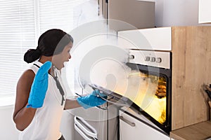 Shocked Woman Looking At Burnt Cookies In Oven