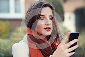 Shocked woman looking at mobile phone