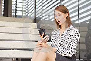 Shocked woman looking at phone reading seeing bad news or photos