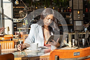 Shocked woman looking with surprise at the digital tablet while sitting in a coffee shop