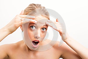 Shocked woman looking at wrinkles on forehead