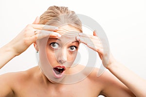 Shocked woman looking at wrinkles on forehead photo