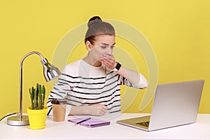 Shocked woman office worker covering mouth, looking at laptop screen with terrified expression.