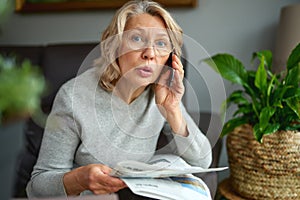 Shocked,woman reading newspaper, bad news.