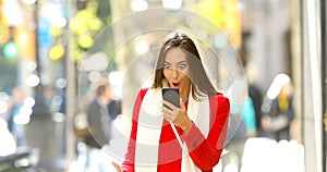 Shocked woman reading online news in the street