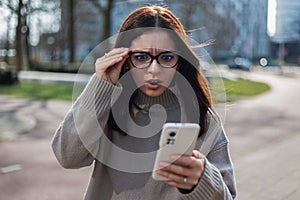 Shocked woman receiving a scam call holding her eyeglasses