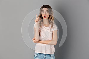 Shocked woman in t-shirt having idea and looking at camera