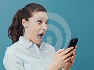 Shocked woman using a smartphone and connecting