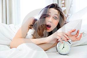 Shocked woman waking up with alarm