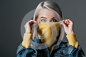 shocked woman in yellow turtleneck and jeans jacket