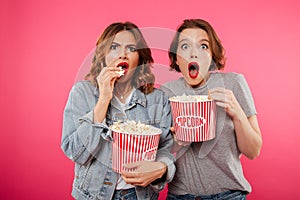 Shocked women friends eating popcorn watch film.