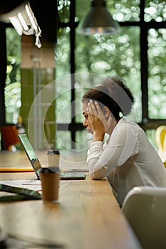 Shocked worried business woman looking at laptop sitting in office